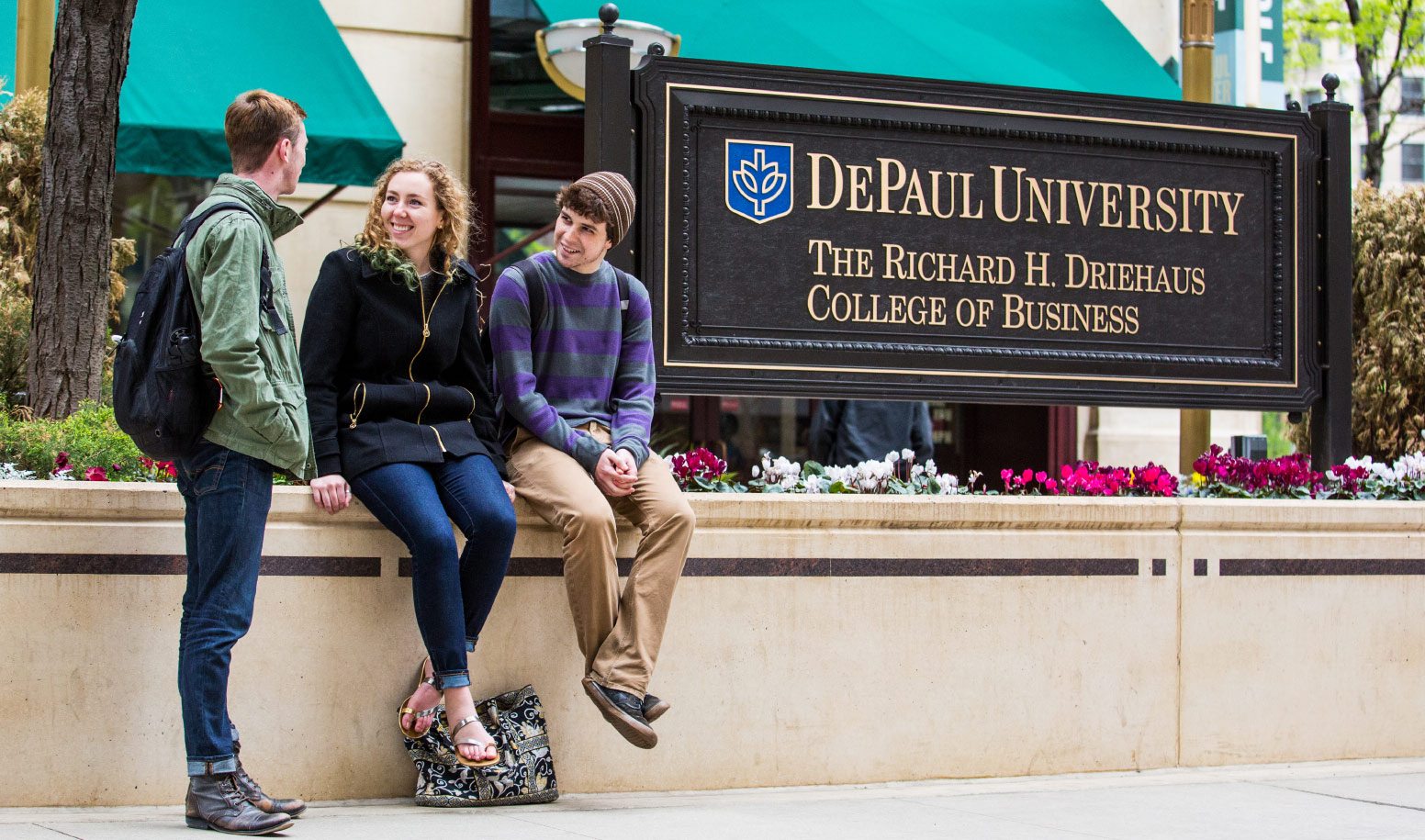 Students sitting near Driehaus College of Business sign