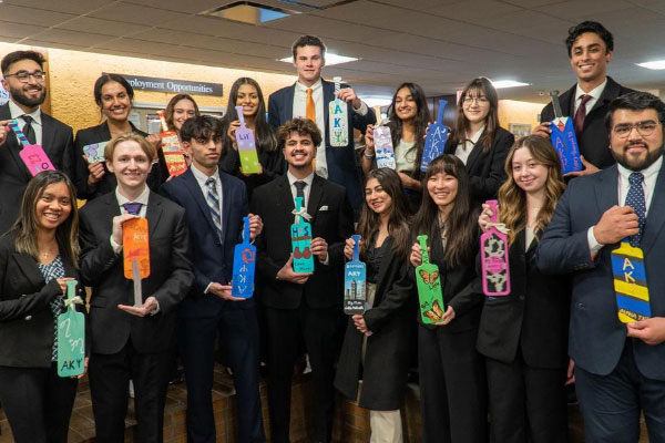 Group of co-ed professional fraternity DePaul students holding paddles
