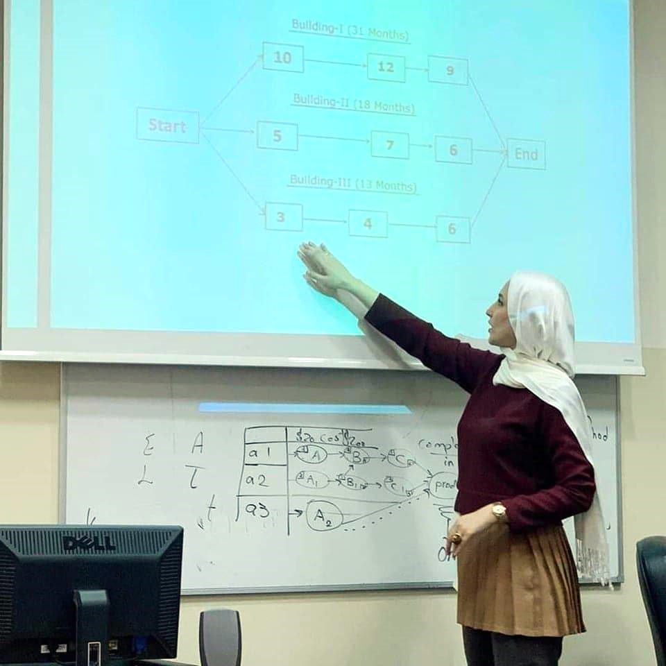 A woman gestures at a board with the stages of entrepreneurship written on it