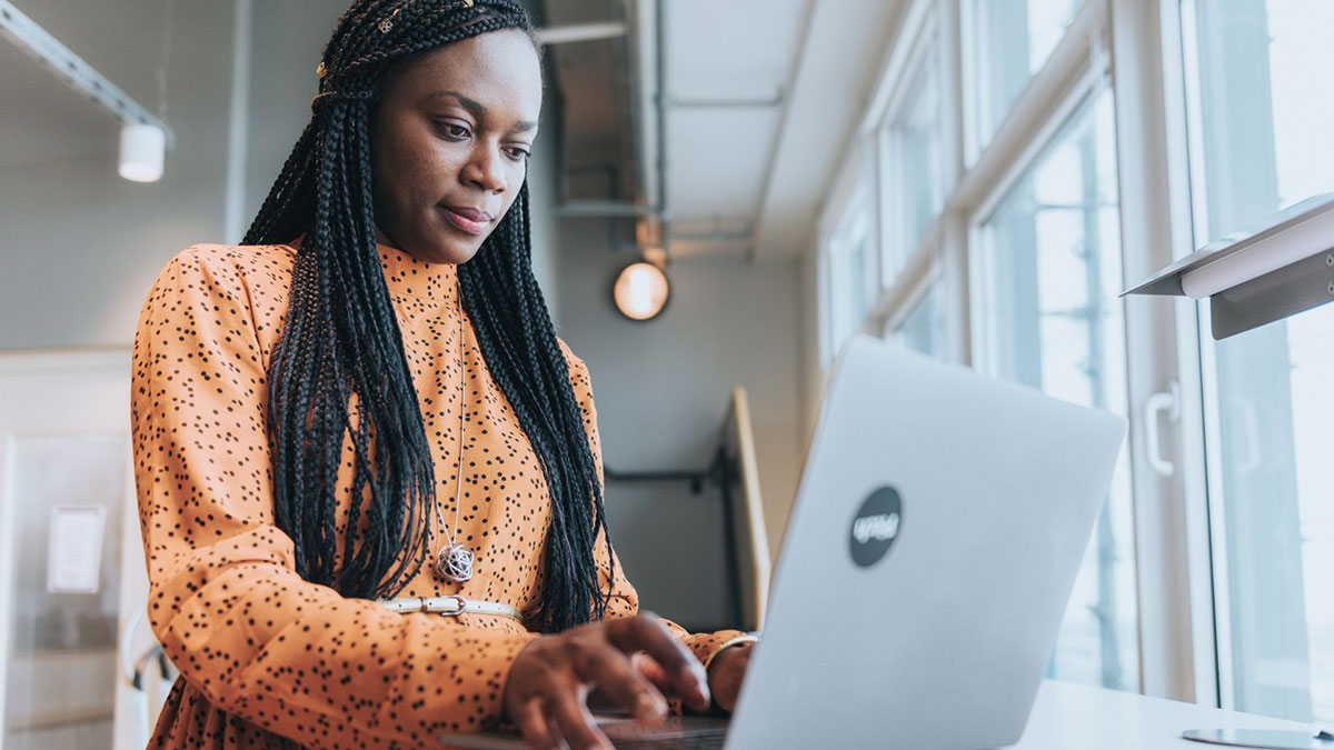 Stock image of a woman of color typing on a laptop.