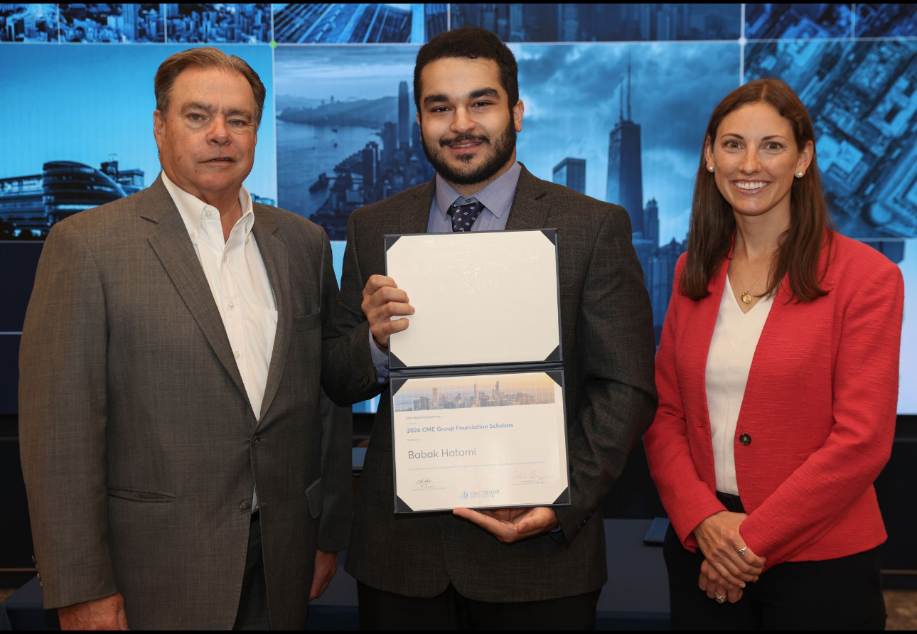 A student in a suit poses holding a certificate with a professional on either side