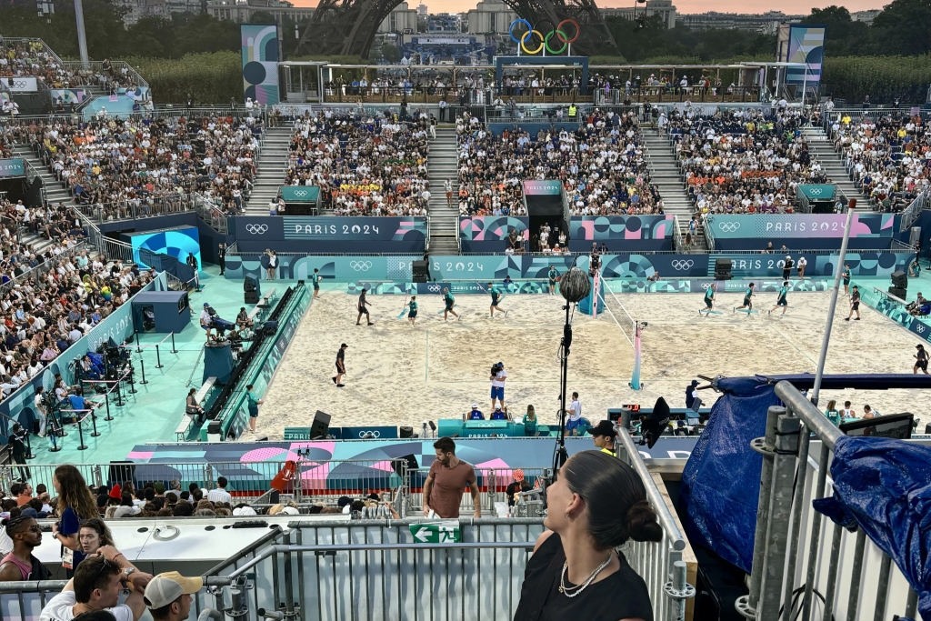 A young woman looks over her shoulder at an Olympic beach volleyball court