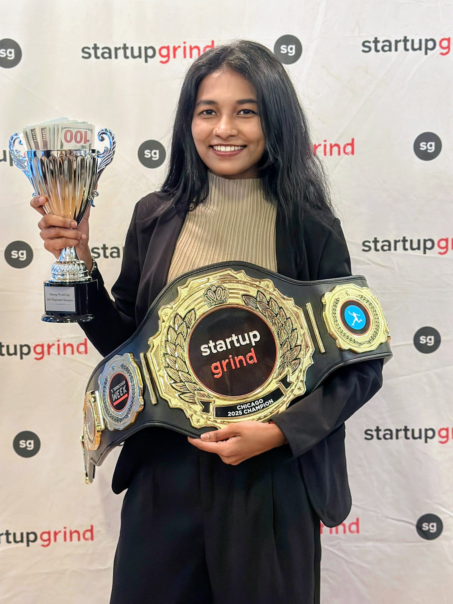 A young woman holds up a celebratory belt and trophy 