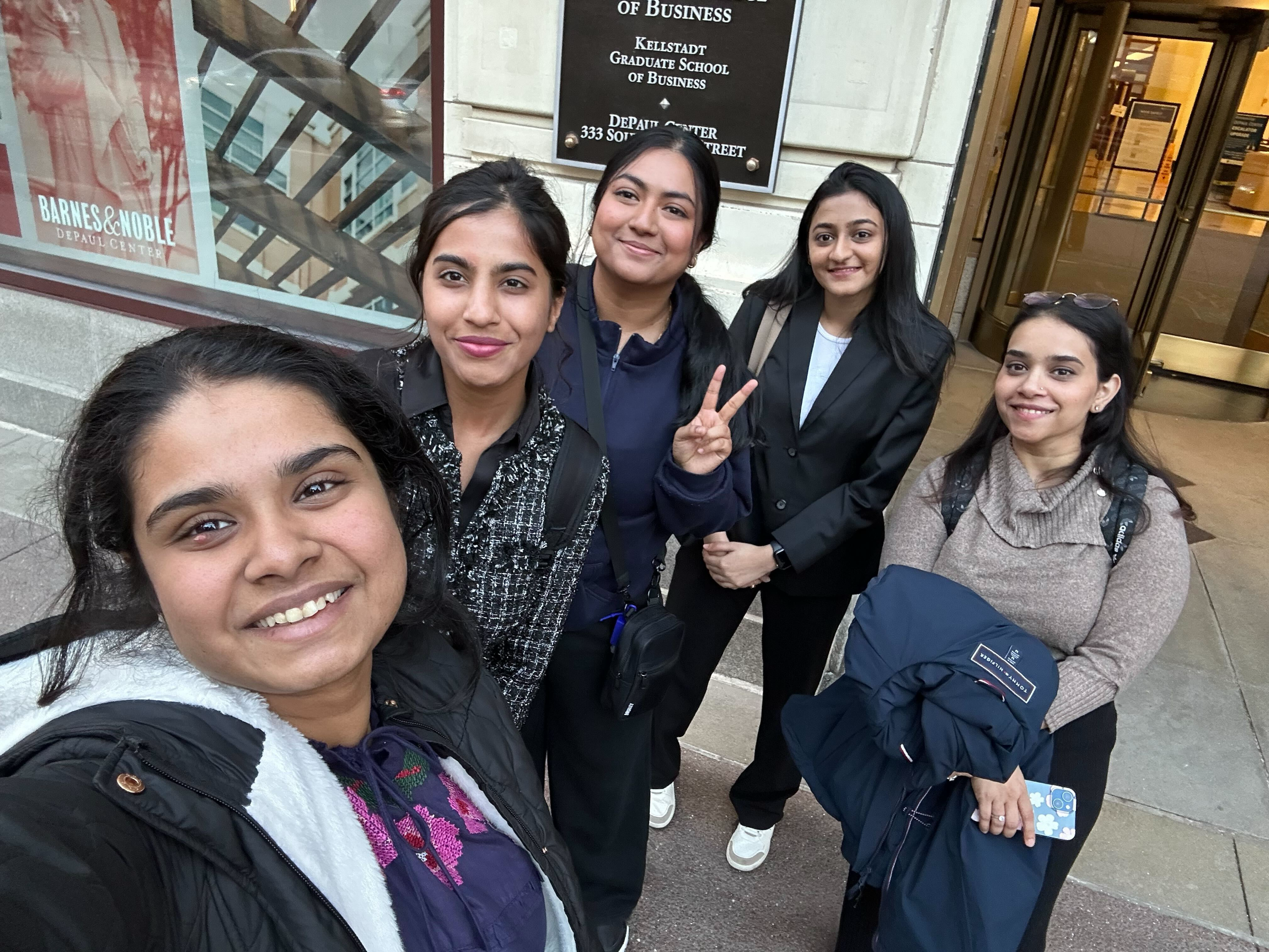 A group of students takes a selfie outside a DePaul campus building