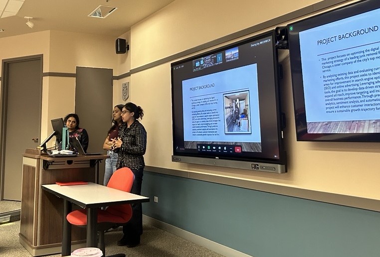 A group of students presents from the front of a classroom