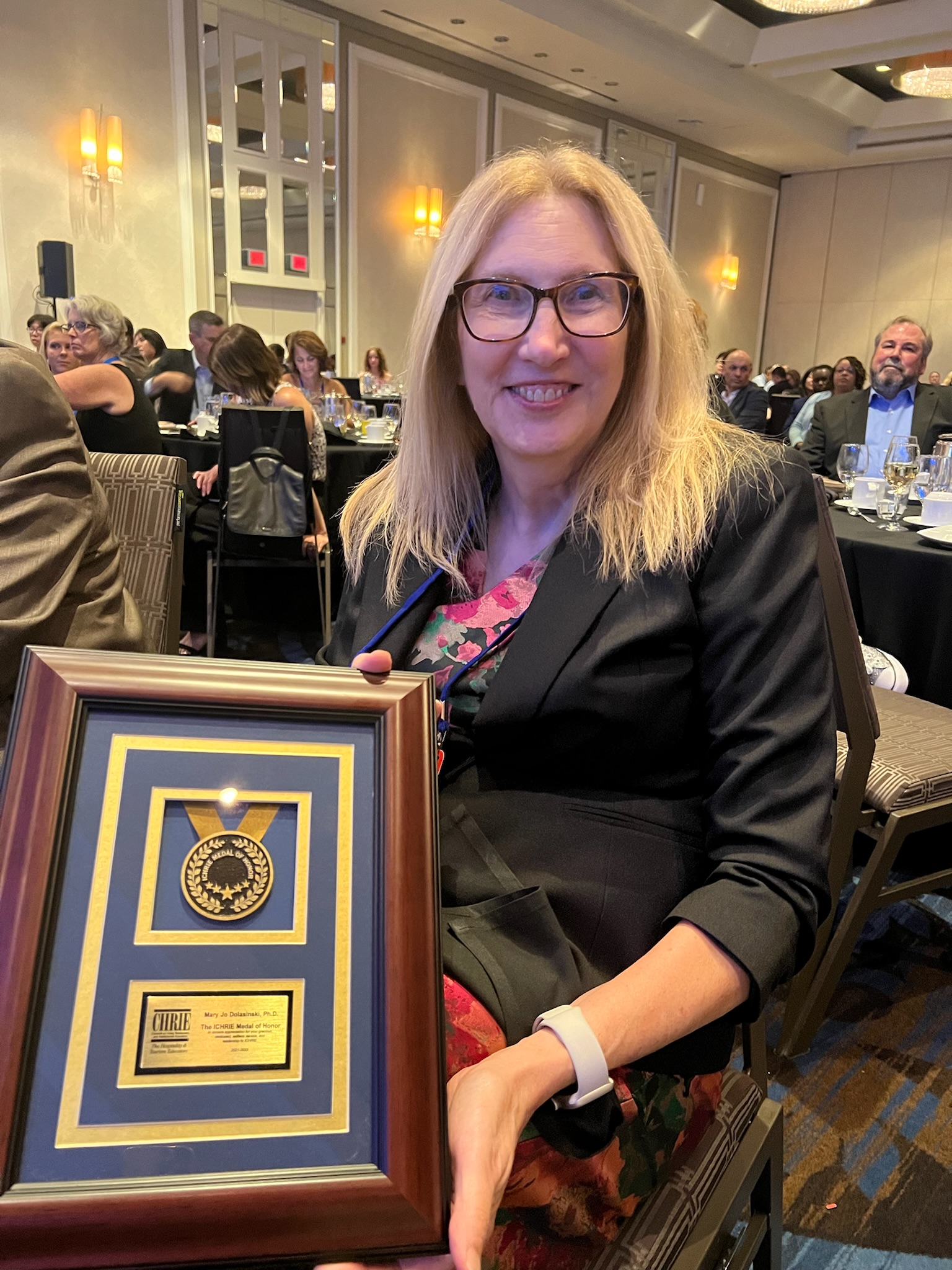 A woman in a suit poses with a large awards plaque