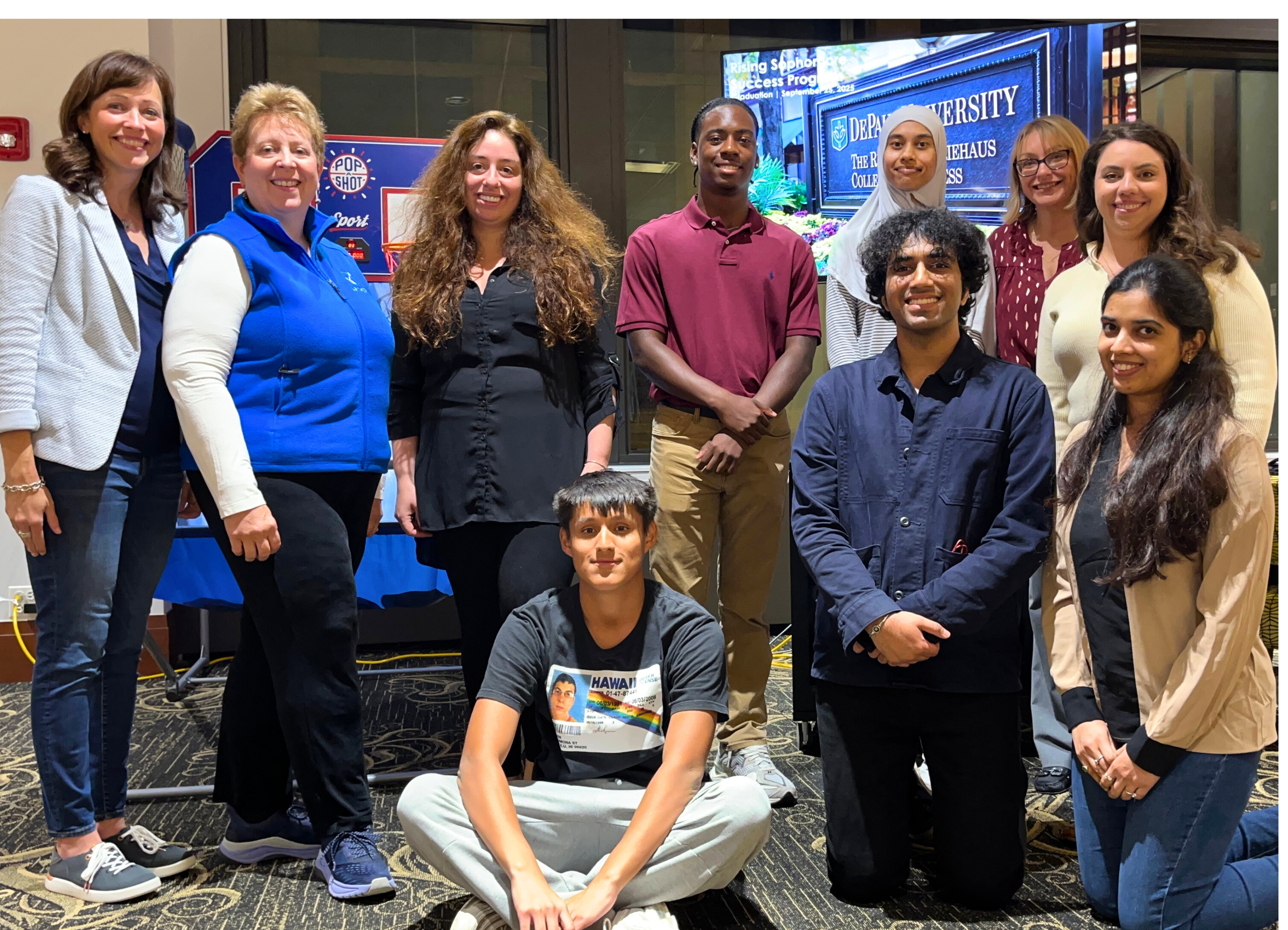 A group of professionals and students in casual clothing pose indoors A group of professionals and students in casual clothing pose indoors