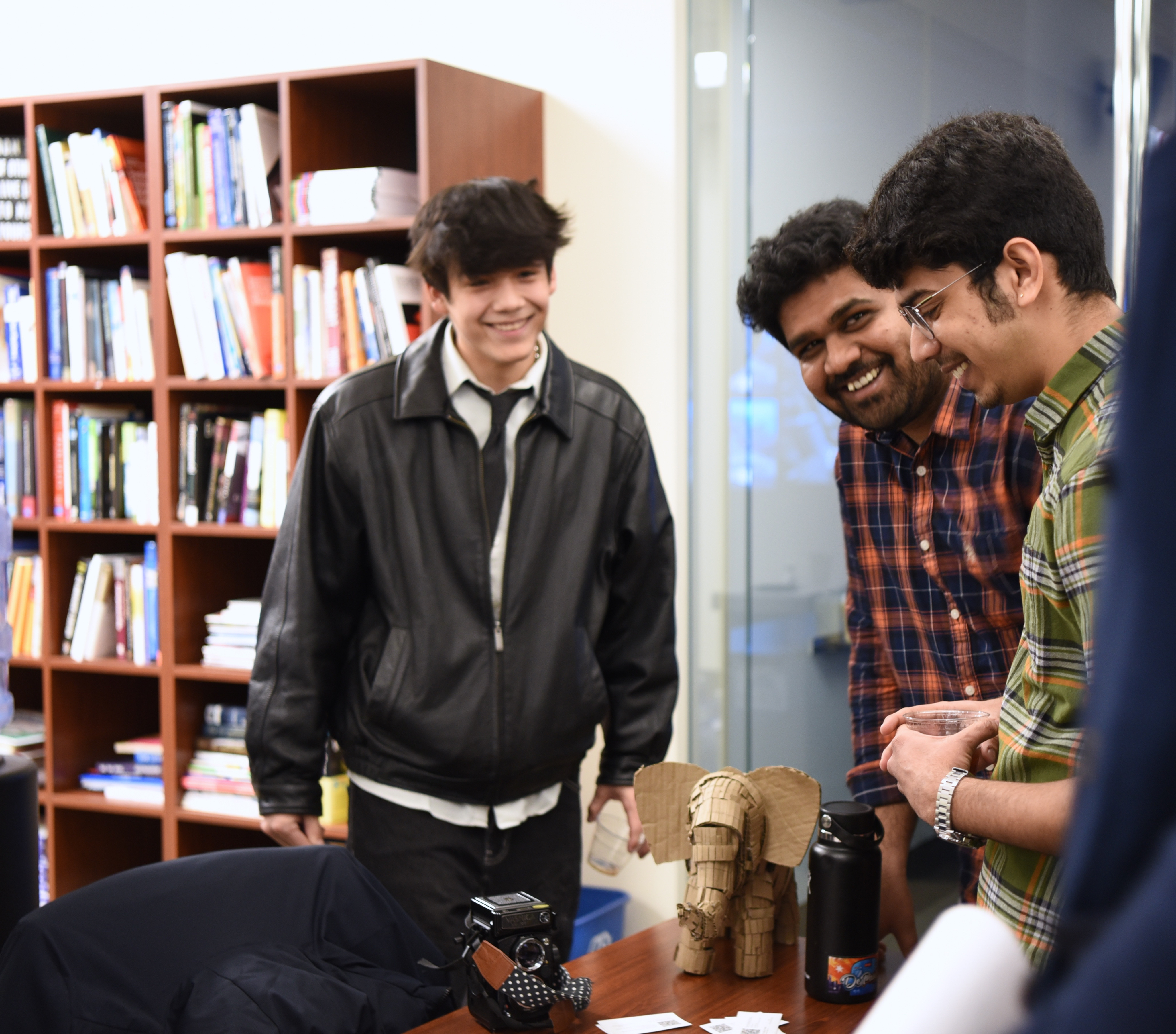 A group of students engaged in a discussion over a table with a handcrafted elephant sculpture