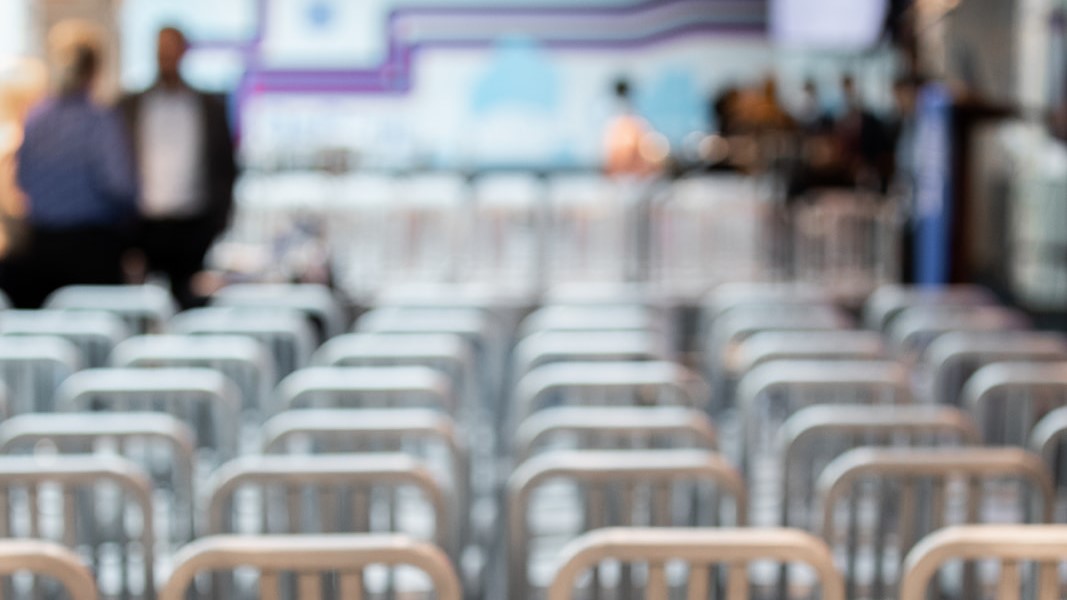A soft-focus of image of empty chairs arranged for a large audience
